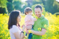 Casal e filha criança no campo de flores amarelas — Fotografia de Stock