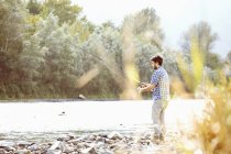 Jeune homme pêchant dans la rivière, Premosello, Verbania, Piemonte, Italie — Photo de stock