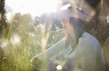 Femme mûre dans un chapeau de cow-boy avec une lame d'herbe dans la bouche — Photo de stock