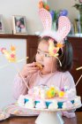 Menina jovem vestindo orelhas de coelho, comer bolo — Fotografia de Stock