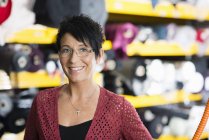 Portrait of mature seamstress in front of textile shelves in workshop — Stock Photo