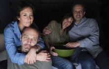 Two mature couples watching TV with snack bowl — Stock Photo