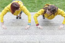 Giovani donne che fanno flessioni sui gradini — Foto stock