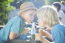 Dois meninos bebendo de garrafa com palhinhas — Fotografia de Stock