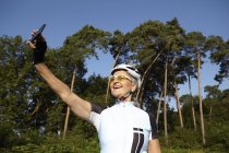 Mature cycliste prendre selfie à côté de la forêt — Photo de stock