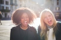 Portrait of two laughing female friends in town square — Stock Photo