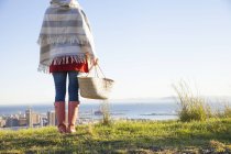 Visão traseira da jovem mulher na colina com vista para o mar — Fotografia de Stock