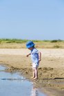 Niño pequeño en la playa arrojando arena al mar, Marennes, Charente-Maritime, Francia - foto de stock