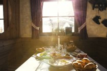 Sunlit breakfast served table in log cabin — Stock Photo