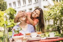 Two female friends in garden coverings eyes with hands — Stock Photo
