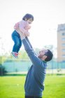Homem adulto médio levantando a filha da criança no parque — Fotografia de Stock