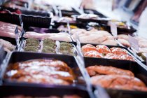 Varietà di prodotti a base di carne fresca in frigorifero in macelleria — Foto stock