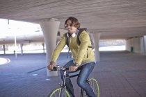 Mid adult man cycling through city underpass — Stock Photo