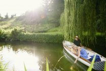 Junge Frau berührt mit Freund Wasser von Fluss-Ruderboot — Stockfoto
