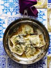 Still life with pan of Italian stinging nettle tortellini and parmesan — Stock Photo