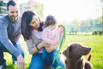 Пара з немовлям дочкою і собакою в парку — стокове фото