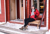 Porträt einer jungen Skifahrerin, die auf der Veranda sitzt, posio, Lappland, Finnland — Stockfoto