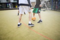 Група дорослих, які грають у футбол на міському футбольному полі, низька секція — стокове фото