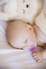 Baby girl sleeping in crib with cuddly toy — Stock Photo