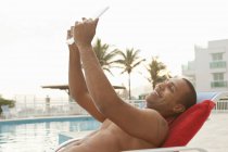 Homme adulte moyen prenant selfie tablette numérique à la piscine de l'hôtel, Rio De Janeiro, Brésil — Photo de stock
