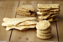 Variety of homemade crackers stacked on wooden surface — Stock Photo