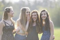 Четыре девочки-подростки в платьях из ромашки хихикают в парке — стоковое фото