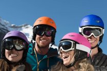 Four friends wearing ski helmets and goggles, laughing — Stock Photo