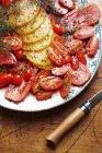 Различные помидоры нарезанные и приправленные на тарелке — стоковое фото