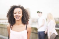 Young woman laughing on city street, people in background — Stock Photo
