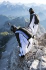 Two male BASE jumpers preparing to launch from mountain, Dolomites, Italy — Stock Photo