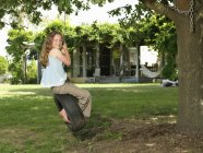 Menina balançando no pneu swing no jardim — Fotografia de Stock