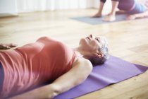 Mature woman lying on back in pilates class — Stock Photo