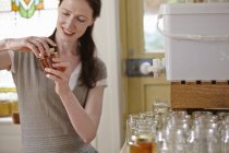 Apicoltore donna in cucina, imbottigliamento miele filtrato da alveare — Foto stock