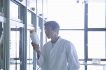 Молодий вчений-чоловік дивиться на пластикову пляшку в лабораторії — стокове фото