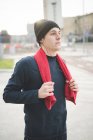 Jovem corredor masculino com toalha em torno de seu pescoço fazendo uma pausa na cidade — Fotografia de Stock