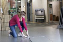 Female customer measuring floor tiles in hardware store — Stock Photo