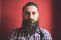 Portrait of young bearded man, red background — Stock Photo