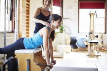 Young female student pushing up from combo chair in pilates gym — Stock Photo