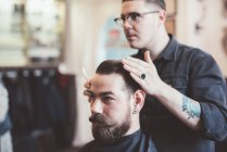 Barber styling client hair in barber shop — Stock Photo