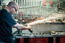 Mécanicien mâle meulage de métal en atelier — Photo de stock