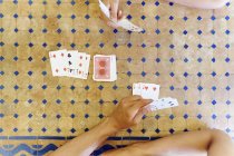 Overhead cropped shot of mature woman and son playing cards at table — Stock Photo