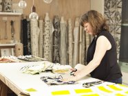 Жінка ріже тканину на робочому столі в друкованій текстильній майстерні — стокове фото