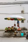 Umbrella over fruit cart on city street — Stock Photo
