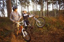 Irmãos gêmeos segurando bicicletas BMX conversando na floresta — Fotografia de Stock