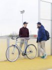 Ciclisti urbani che chattano vicino alla recinzione sul campo sportivo — Foto stock