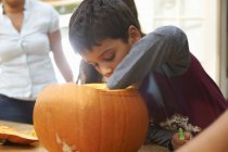 Mother and boy hollowing out pumpkin in dining room — Stock Photo