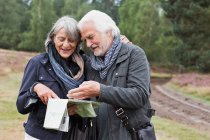Seniorenpaar schaut tagsüber im Wald auf Landkarte — Stockfoto