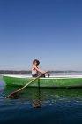 Mulher remo barco em lago ainda — Fotografia de Stock