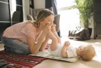 Mother kissing baby feet at home — Stock Photo