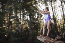 Молодая девушка с помощью веревки качели над озером — стоковое фото